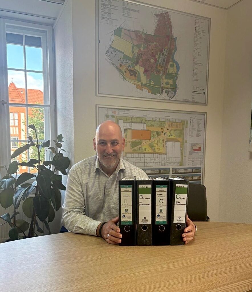Bürgermeister Frank Nerlich in seinem Büro mit der Baugenehmigung in seinen Händen.